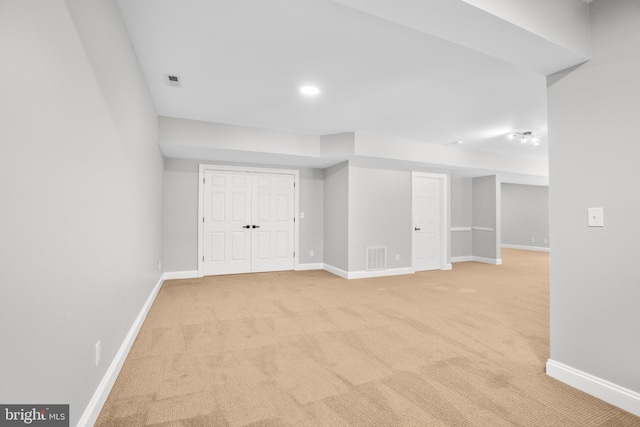 finished below grade area with light carpet, baseboards, and recessed lighting