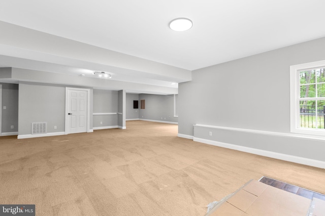 basement featuring baseboards and light colored carpet