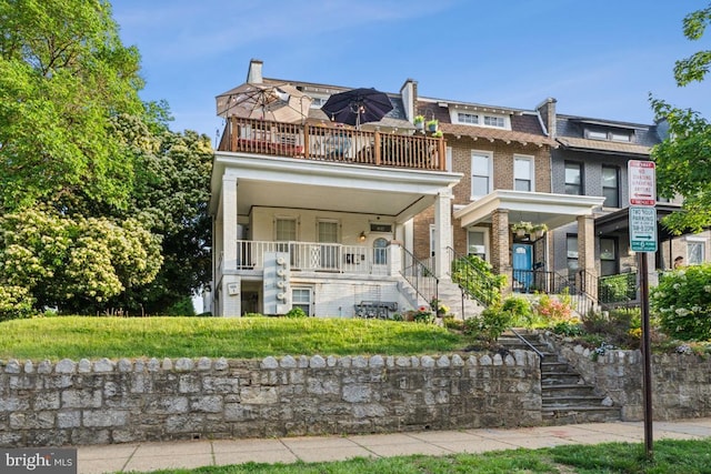 townhome / multi-family property featuring a balcony, mansard roof, brick siding, a porch, and stairway