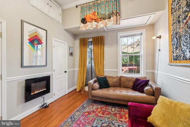 living area featuring baseboards, a glass covered fireplace, and wood finished floors