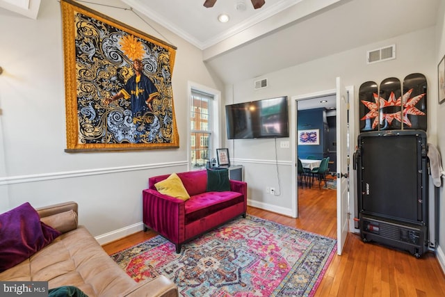 living area featuring visible vents, ornamental molding, a ceiling fan, and wood finished floors