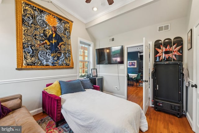 bedroom with crown molding, visible vents, and wood finished floors