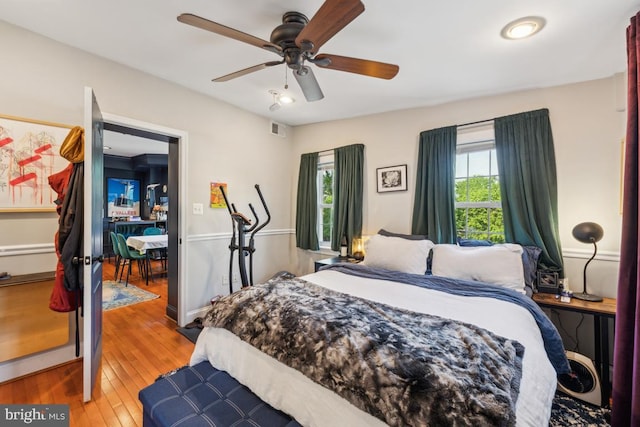 bedroom with visible vents, wood-type flooring, ceiling fan, and multiple windows