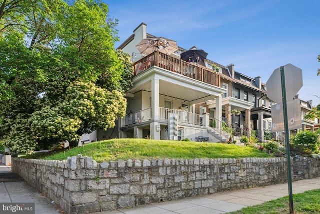 view of front of home with a balcony and stairs