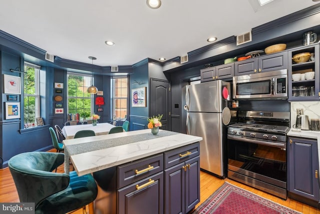 kitchen with crown molding, visible vents, a breakfast bar, light wood-style flooring, and stainless steel appliances