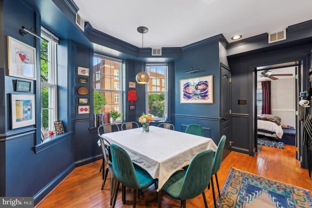 dining space featuring visible vents, a ceiling fan, crown molding, and hardwood / wood-style floors
