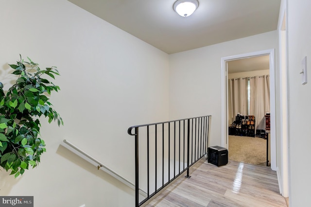 corridor featuring light wood-type flooring and an upstairs landing