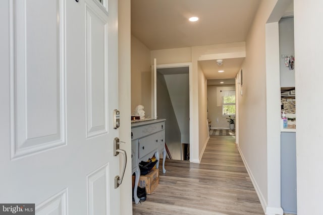 corridor featuring baseboards, recessed lighting, and light wood-style flooring