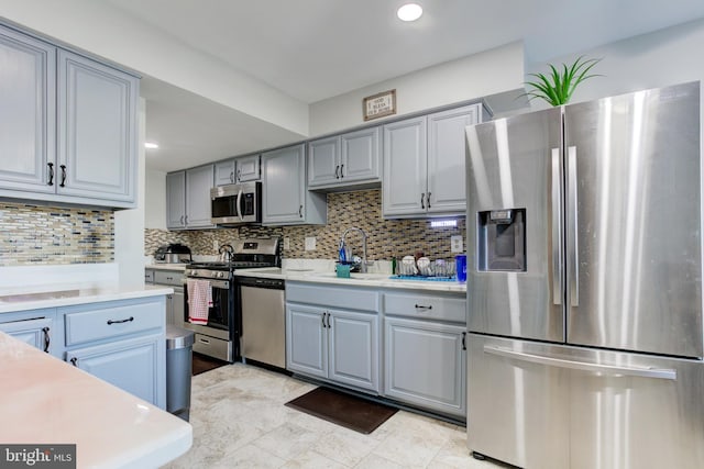 kitchen with a sink, appliances with stainless steel finishes, gray cabinetry, and light countertops