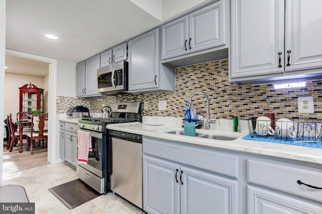 kitchen with recessed lighting, tasteful backsplash, a sink, appliances with stainless steel finishes, and gray cabinetry