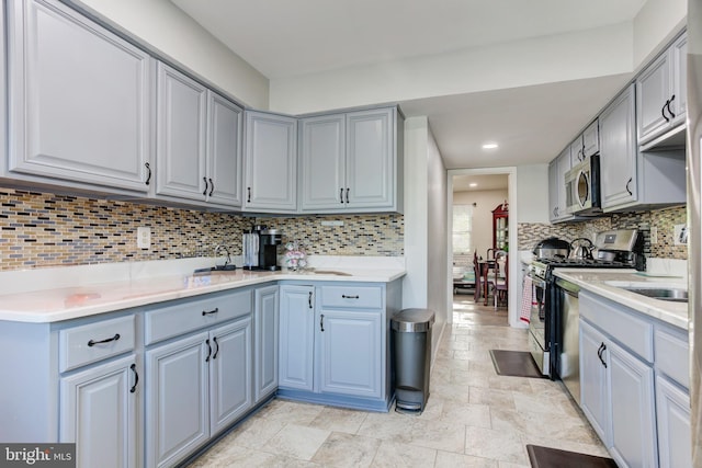 kitchen with light countertops, stainless steel appliances, gray cabinetry, and tasteful backsplash