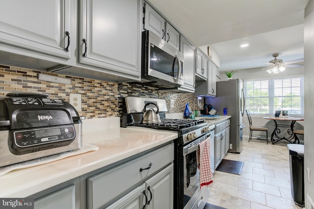 kitchen with backsplash, stainless steel appliances, a ceiling fan, and light countertops