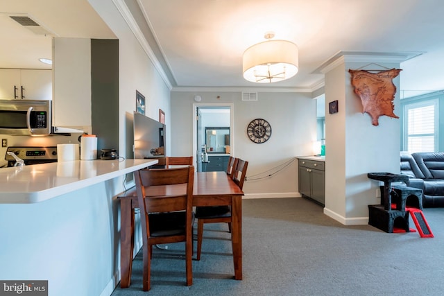 dining space with visible vents, baseboards, crown molding, and dark colored carpet