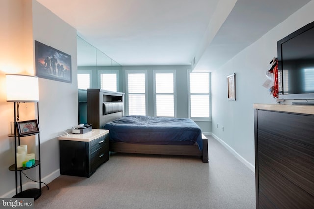 bedroom featuring baseboards, multiple windows, and light carpet
