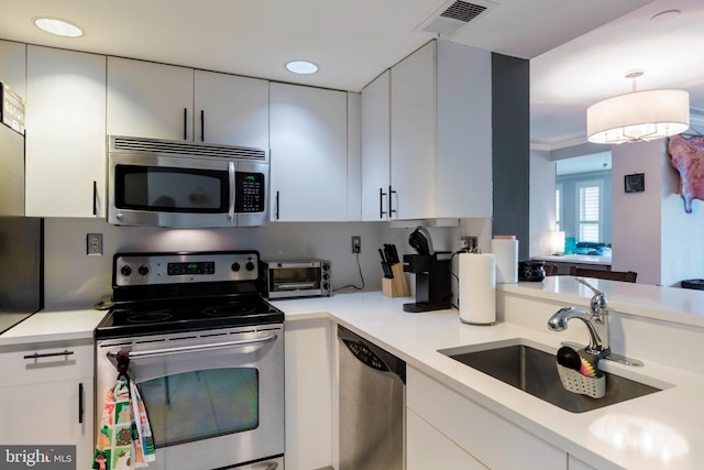 kitchen with visible vents, a sink, light countertops, stainless steel appliances, and white cabinetry