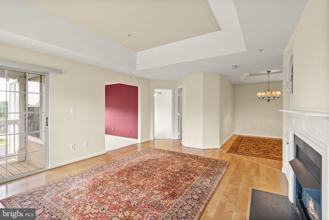 8075 Lacy Dr Unit 303, Manassas, VA 20109 - unfurnished living room featuring an inviting chandelier, wood finished floors, a fireplace with flush hearth, baseboards, and a raised ceiling