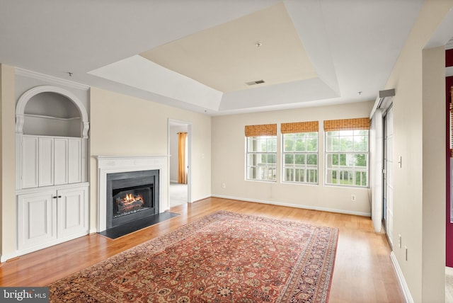 8075 Lacy Dr Unit 303, Manassas, VA 20109 - unfurnished living room featuring wood finished floors, a tray ceiling, a fireplace with flush hearth, visible vents, and baseboards