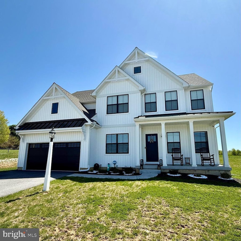 modern farmhouse featuring a porch, board and batten siding, a standing seam roof, driveway, and a front lawn