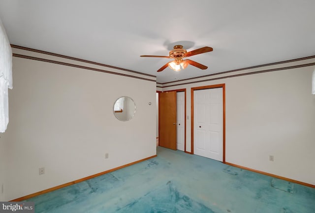 unfurnished bedroom with crown molding, light colored carpet, multiple closets, a ceiling fan, and baseboards