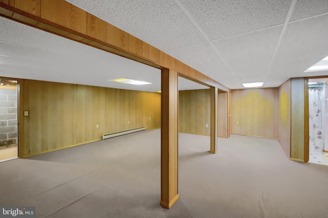 finished below grade area with wooden walls, carpet floors, and a baseboard heating unit
