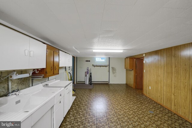 laundry room with wooden walls, dark floors, washer / clothes dryer, and a sink