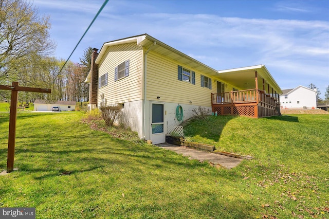 rear view of house with a wooden deck, a chimney, and a yard