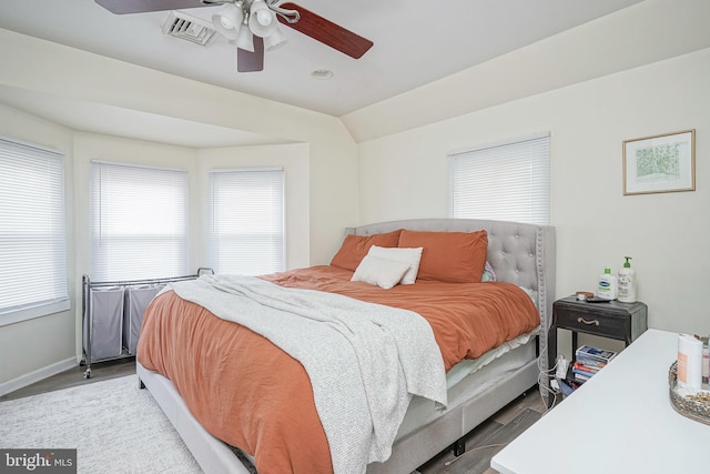 bedroom featuring a ceiling fan, visible vents, wood finished floors, baseboards, and lofted ceiling