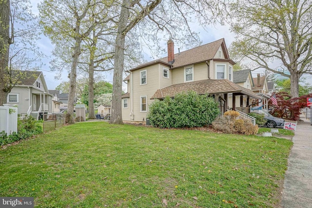 view of home's exterior with a porch, a chimney, a residential view, fence, and a yard