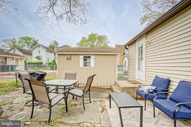 view of patio featuring a storage unit, fence, an outbuilding, and outdoor dining space