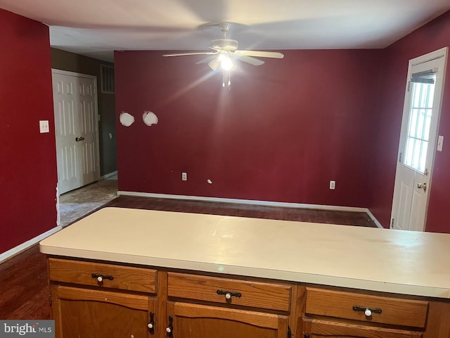 kitchen featuring light countertops, brown cabinetry, a ceiling fan, baseboards, and visible vents