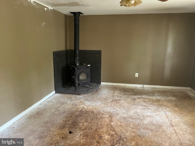 unfurnished living room featuring baseboards and a wood stove