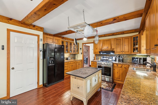kitchen featuring beamed ceiling, light stone countertops, a sink, tasteful backsplash, and appliances with stainless steel finishes