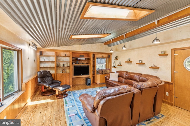 living area with built in features, vaulted ceiling with beams, wooden walls, a wainscoted wall, and wood finished floors