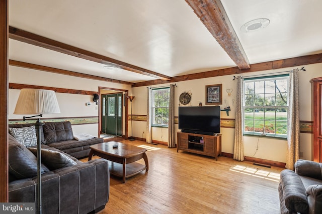 living area with baseboards, visible vents, beamed ceiling, and light wood finished floors