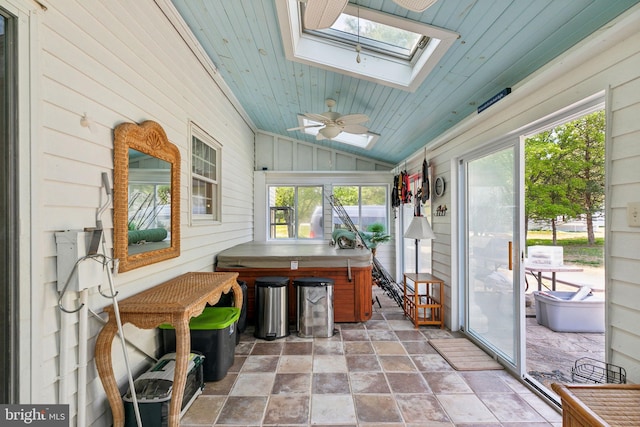 sunroom featuring a jacuzzi, ceiling fan, a healthy amount of sunlight, and a skylight