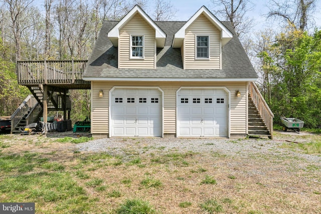 view of home's exterior featuring a detached garage, stairway, a wooden deck, and roof with shingles