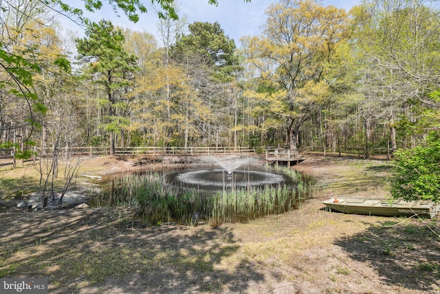 view of yard with fence, a water view, and a wooded view