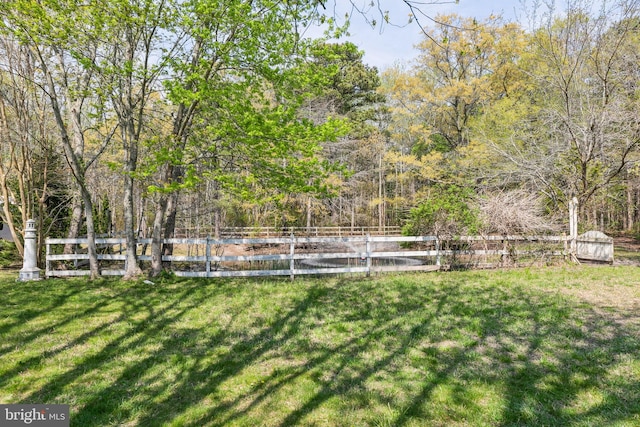 view of yard featuring a wooded view, a water view, and fence