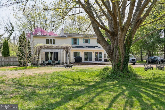 rear view of house featuring fence and a yard