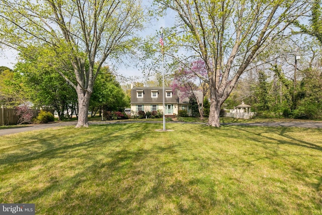 view of front of property with fence, a gazebo, and a front lawn