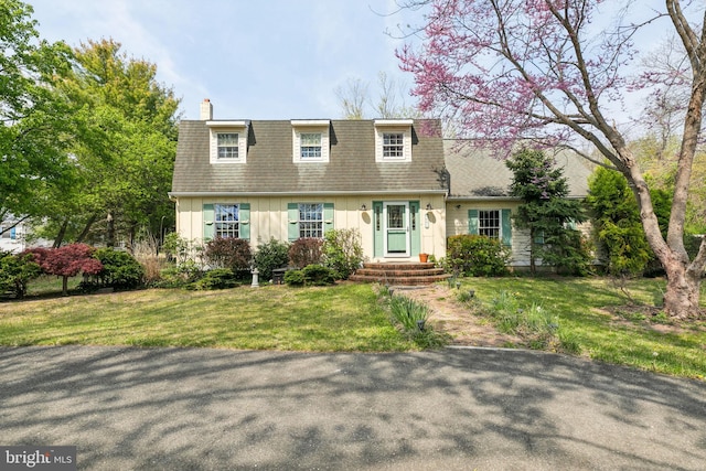 view of front of house featuring a chimney, a front lawn, board and batten siding, and a shingled roof