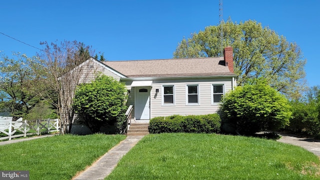 bungalow-style house featuring a front lawn, fence, a chimney, and entry steps