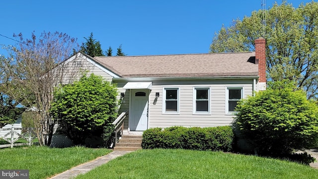 bungalow-style home featuring a chimney and a front lawn