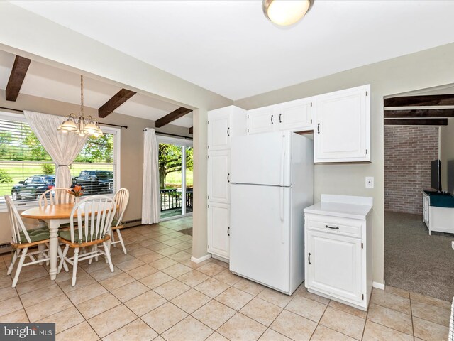 kitchen featuring light tile patterned floors, light countertops, freestanding refrigerator, a chandelier, and white cabinetry