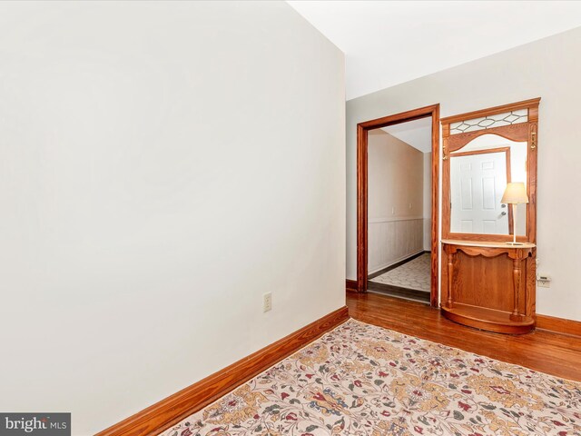 spare room featuring baseboards and wood finished floors