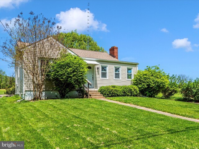 view of front of property with entry steps, a chimney, and a front lawn