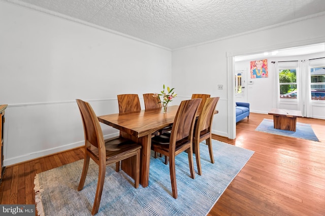 dining space with baseboards, light wood-style flooring, and an ornate ceiling