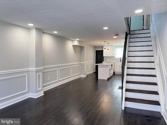 staircase with wainscoting, recessed lighting, and wood finished floors
