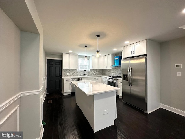 kitchen featuring wall chimney range hood, appliances with stainless steel finishes, backsplash, and dark wood-style flooring
