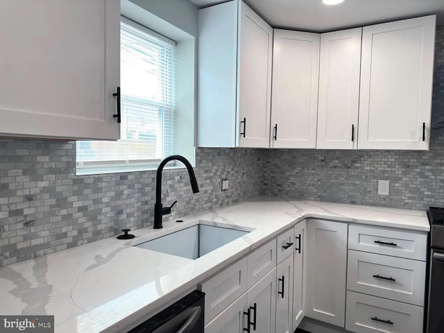 kitchen featuring white cabinetry, light stone countertops, a sink, and tasteful backsplash